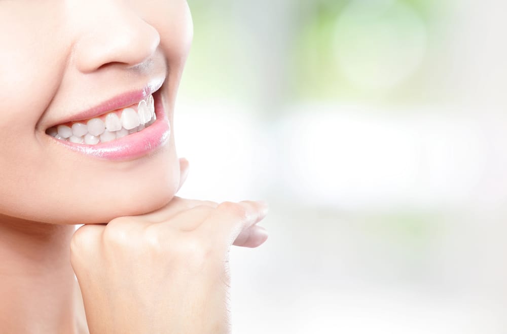 Teeth whitening: a close-up of a smiling person with bright, pearly white teeth.